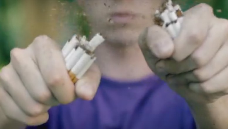 En la imagen, un joven rompe un puñado de cigarrillos.